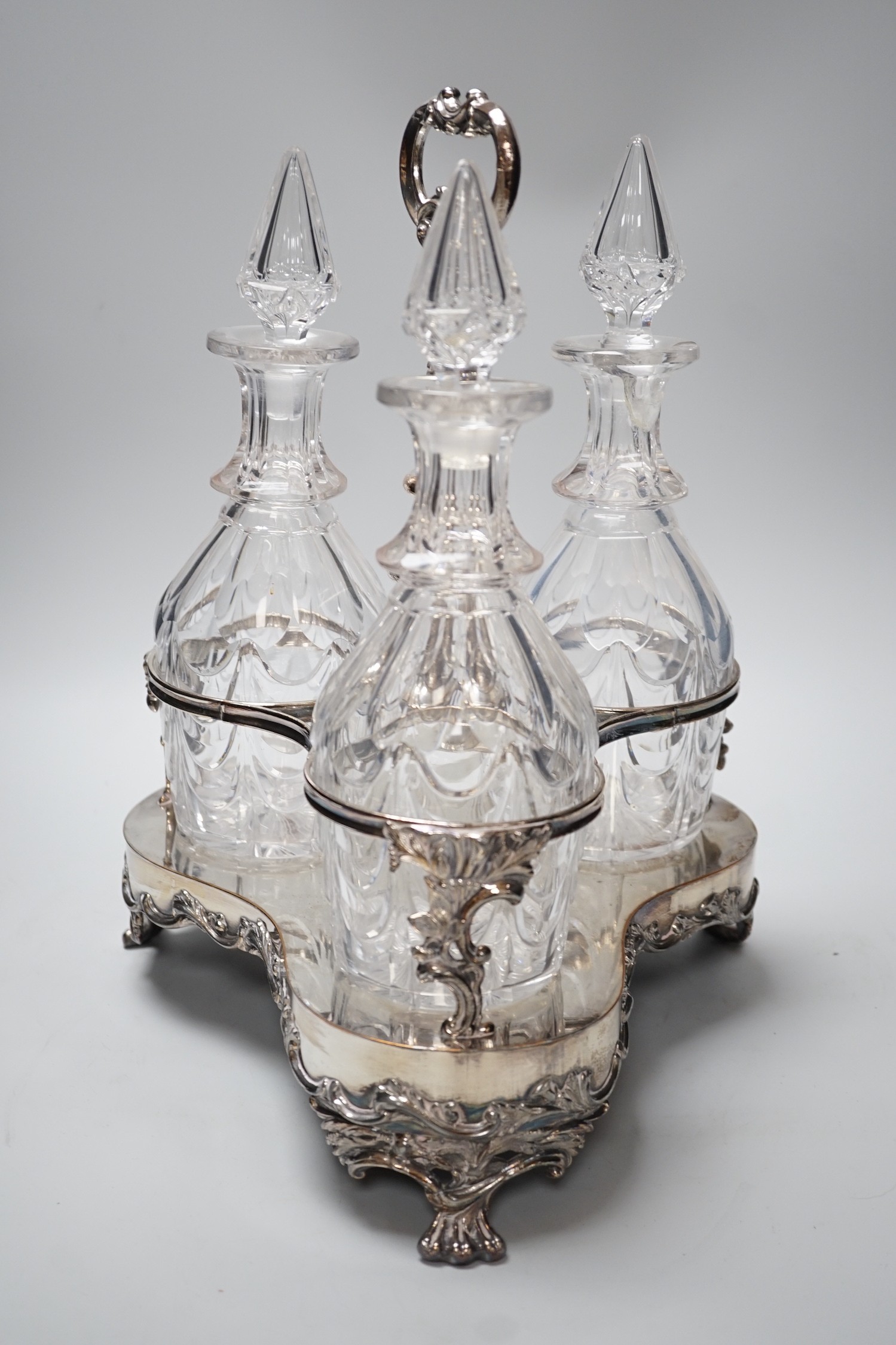 A decorative three bottle decanter set, on lion feet tripod plated stand. 37cm tall